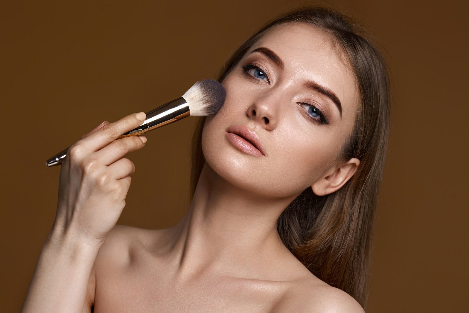woman applying blush on cheeks with make-up brush