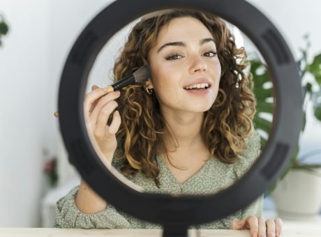 pretty woman putting on makeup at home with light